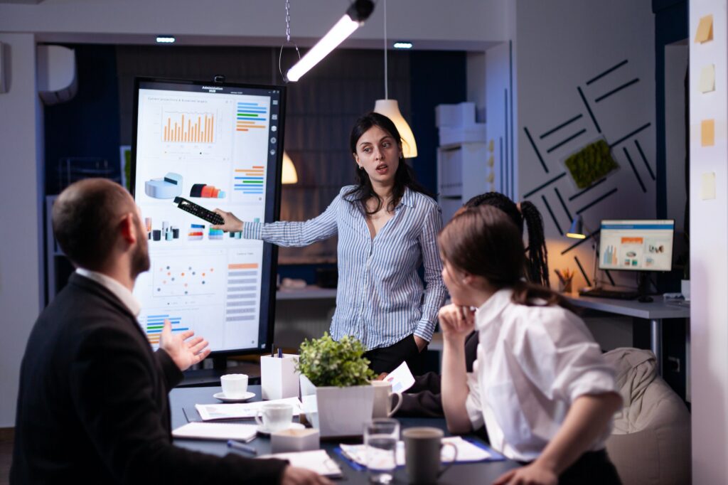 Workaholic focused businesswoman explaining management solution pointing strategy on monitor